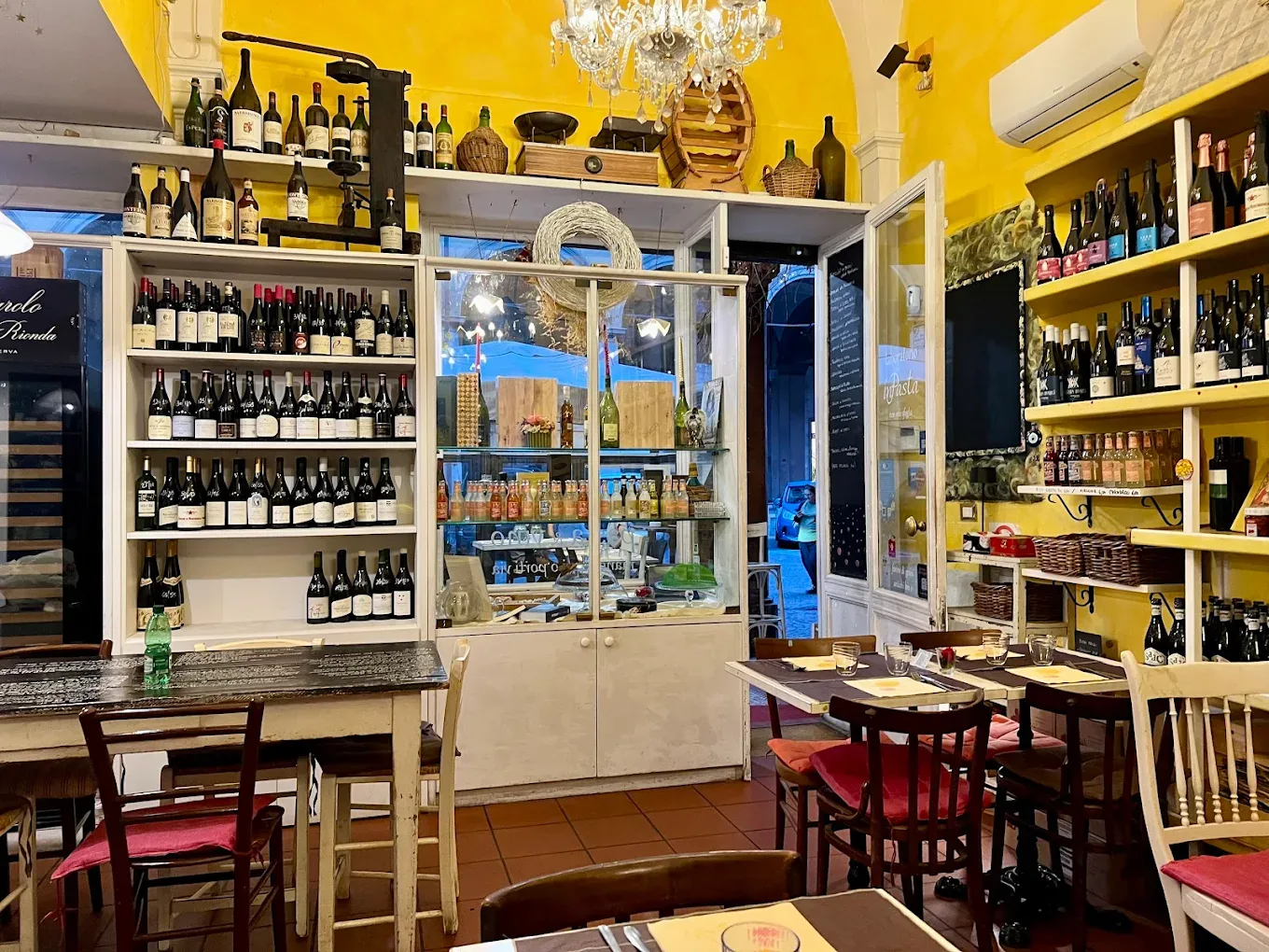 La sala interna con le pareti gialle e gli scaffali pieni di bottiglie di vino
