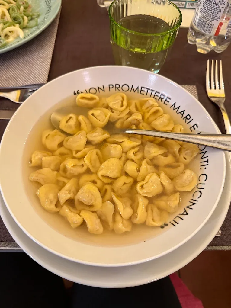 Tortellini in brodo nel piatto con il motto della casa sul bordo